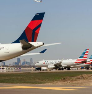 Picture of a runway with planes at Minneapolis St. Paul International Airport with the Minneapolis skyline in the background.