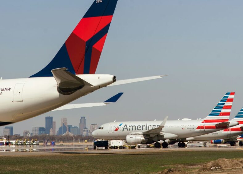 Picture of a runway with planes at Minneapolis St. Paul International Airport with the Minneapolis skyline in the background.